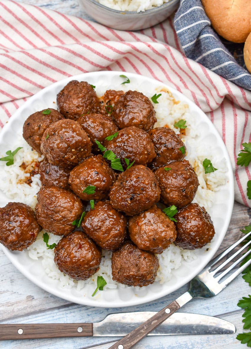 slow cooker brown sugar meatballs over a bed of steamed white rice on a small white plate