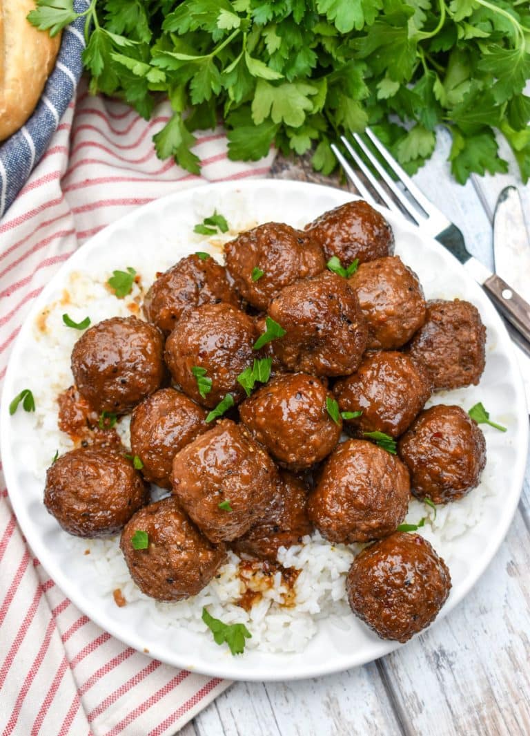 slow cooker brown sugar meatballs over a bed of steamed white rice on a small white plate
