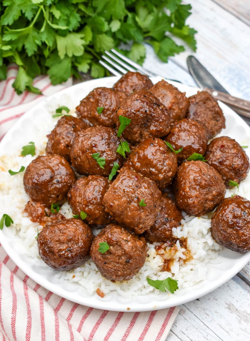 slow cooker brown sugar meatballs over a bed of steamed white rice on a small white plate