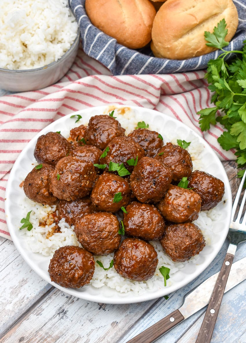 slow cooker brown sugar meatballs over a bed of steamed white rice on a small white plate