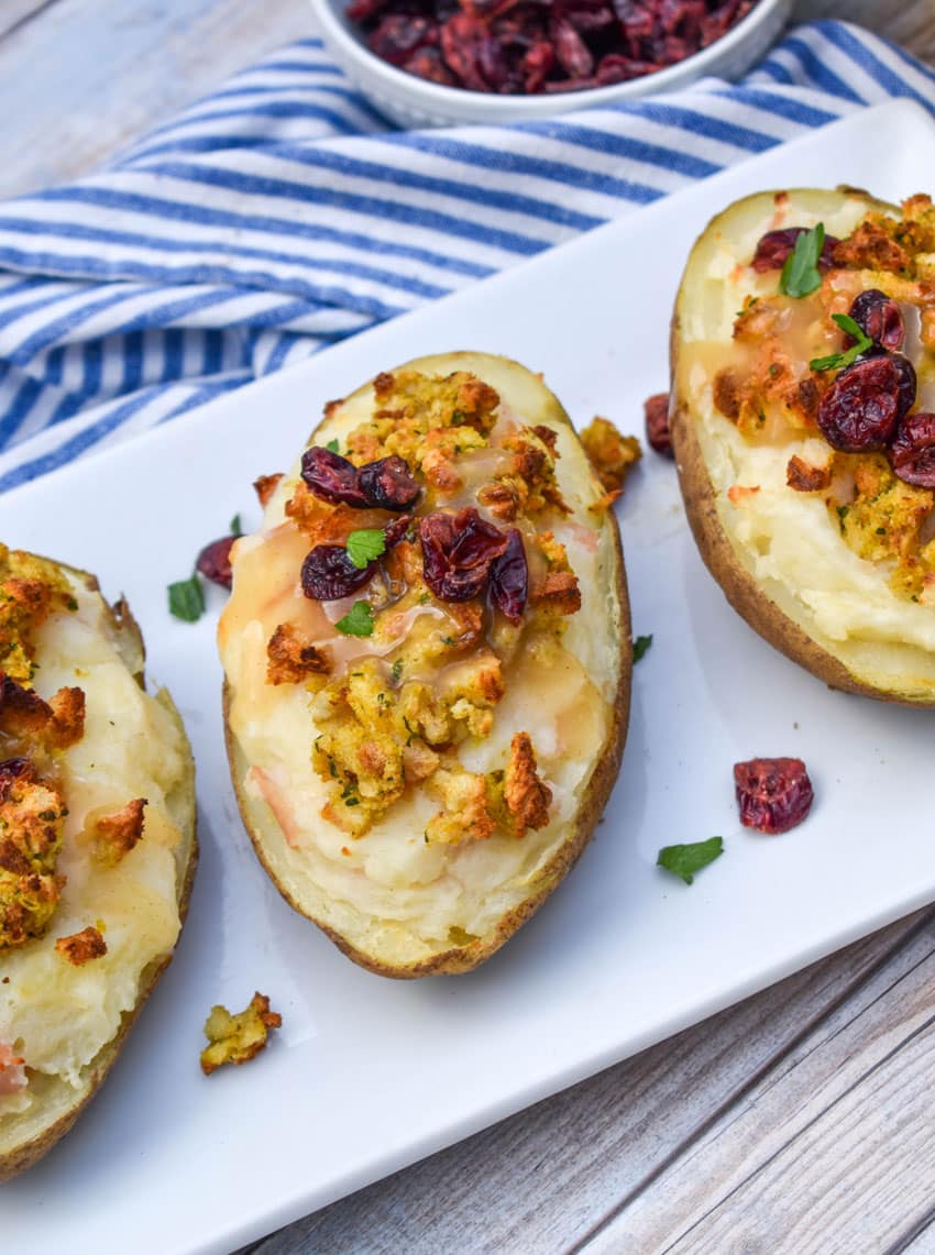 thanksgiving leftover twice baked potatoes arranged in a row on a white serving platter