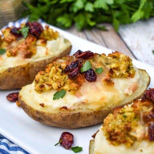 thanksgiving leftover twice baked potatoes arranged in a row on a white serving platter