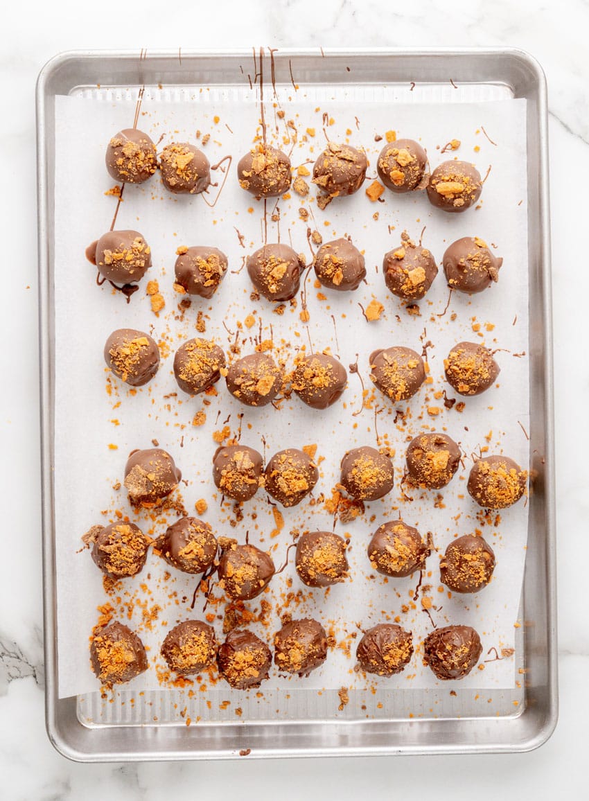 butterfinger truffles arranged in rows on a parchment paper lined baking sheet
