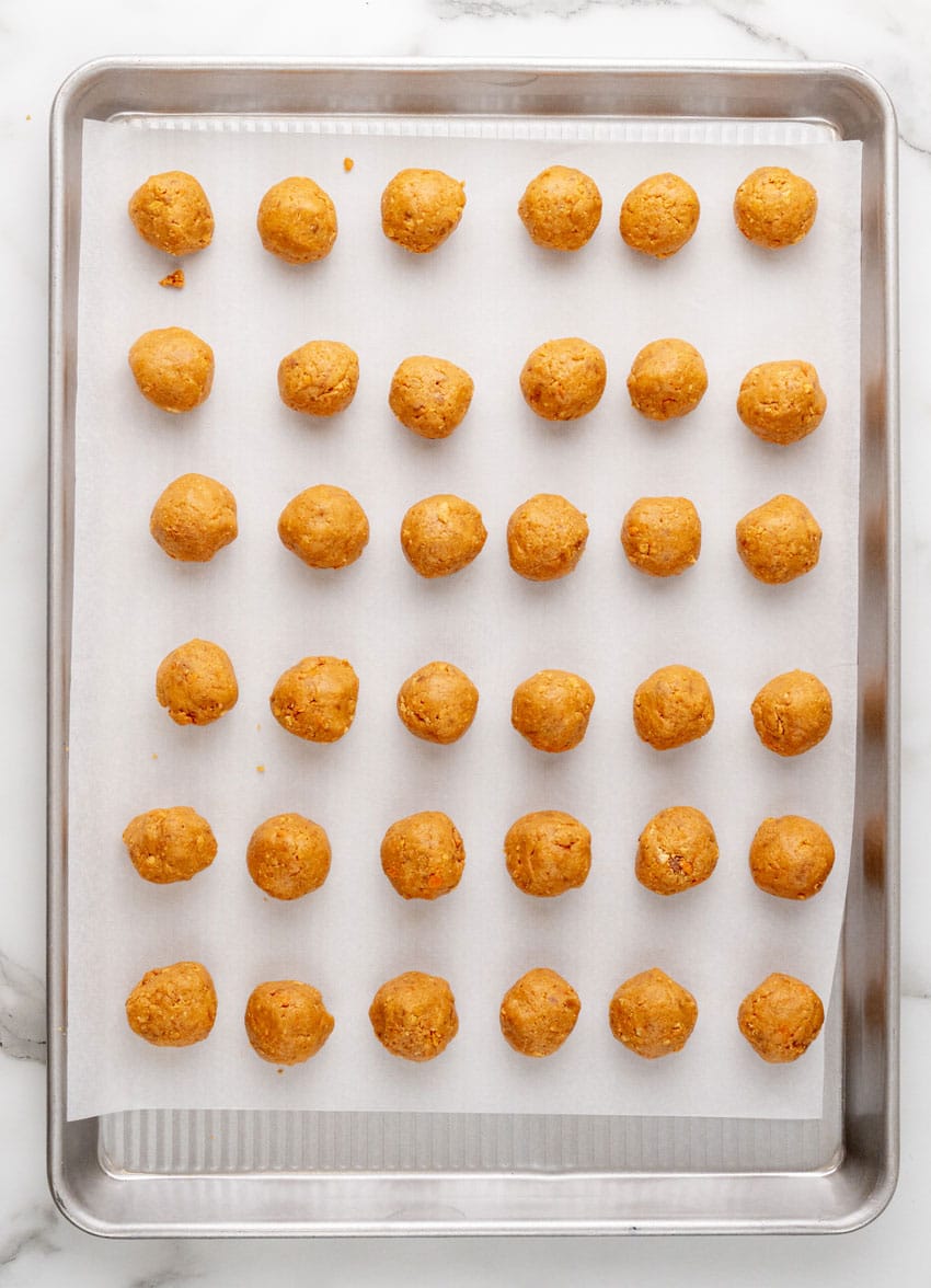 rolled butterfinger balls arranged in rows on a parchment paper lined baking sheet