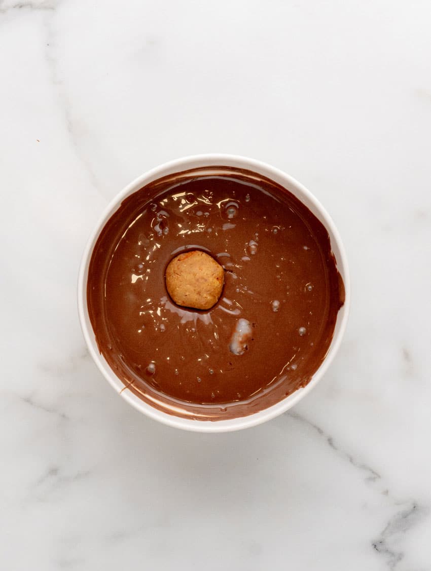 a butterfinger ball in a bowl of melted chocolate