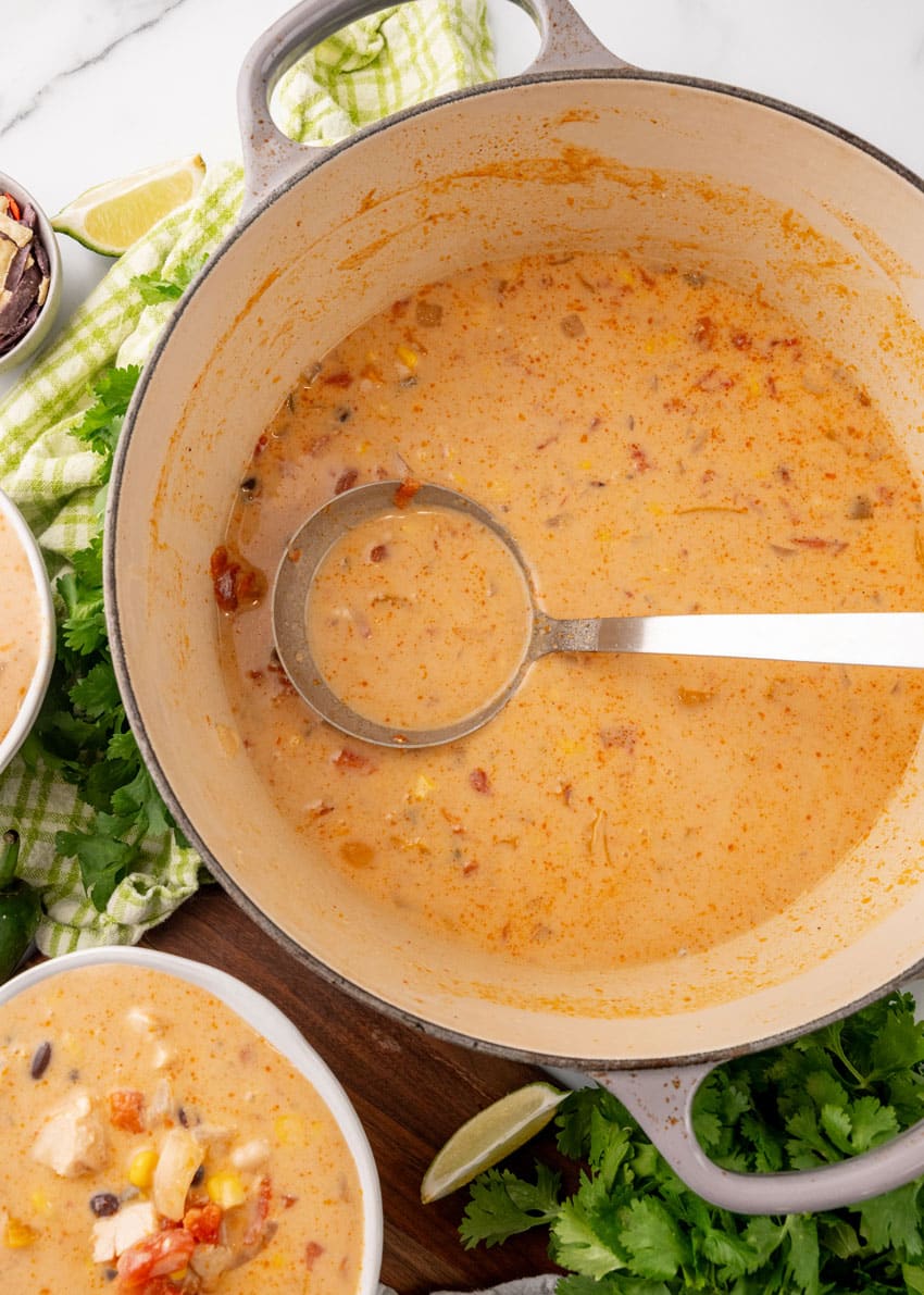 a silver ladle scooping homemade copycat chick fil a chicken tortilla soup out of a large dutch oven