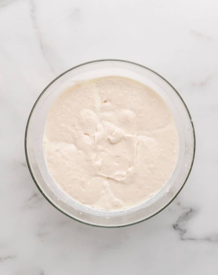 a thick white mixture of blended cream and canned navy beans in a glass mixing bowl