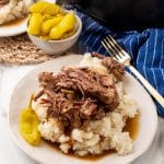 slow cooked mississippi pot roast over mashed potatoes on a white plate