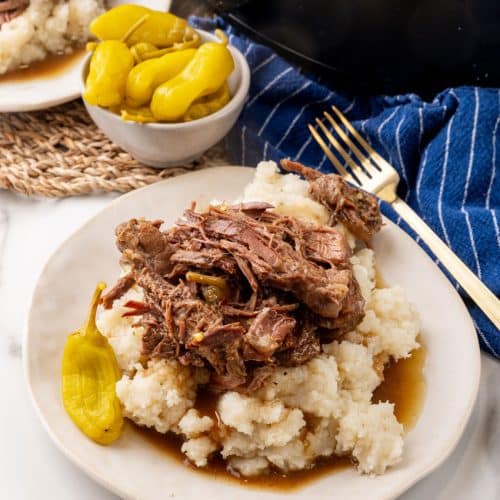 slow cooked mississippi pot roast over mashed potatoes on a white plate