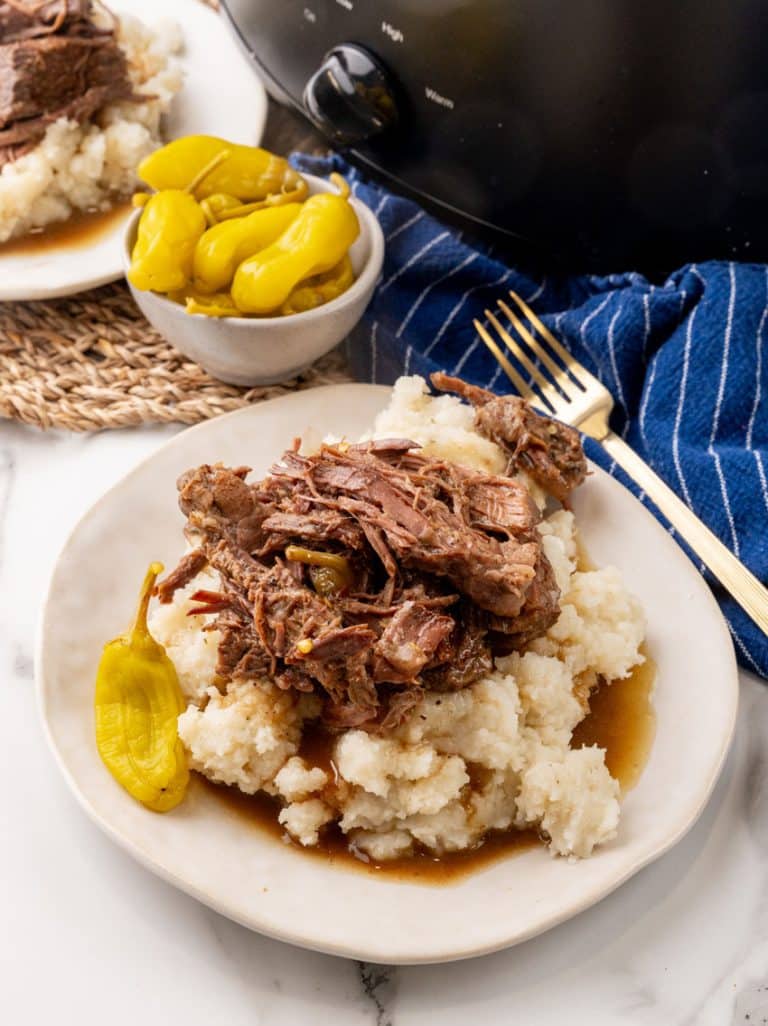 slow cooked mississippi pot roast over mashed potatoes on a white plate