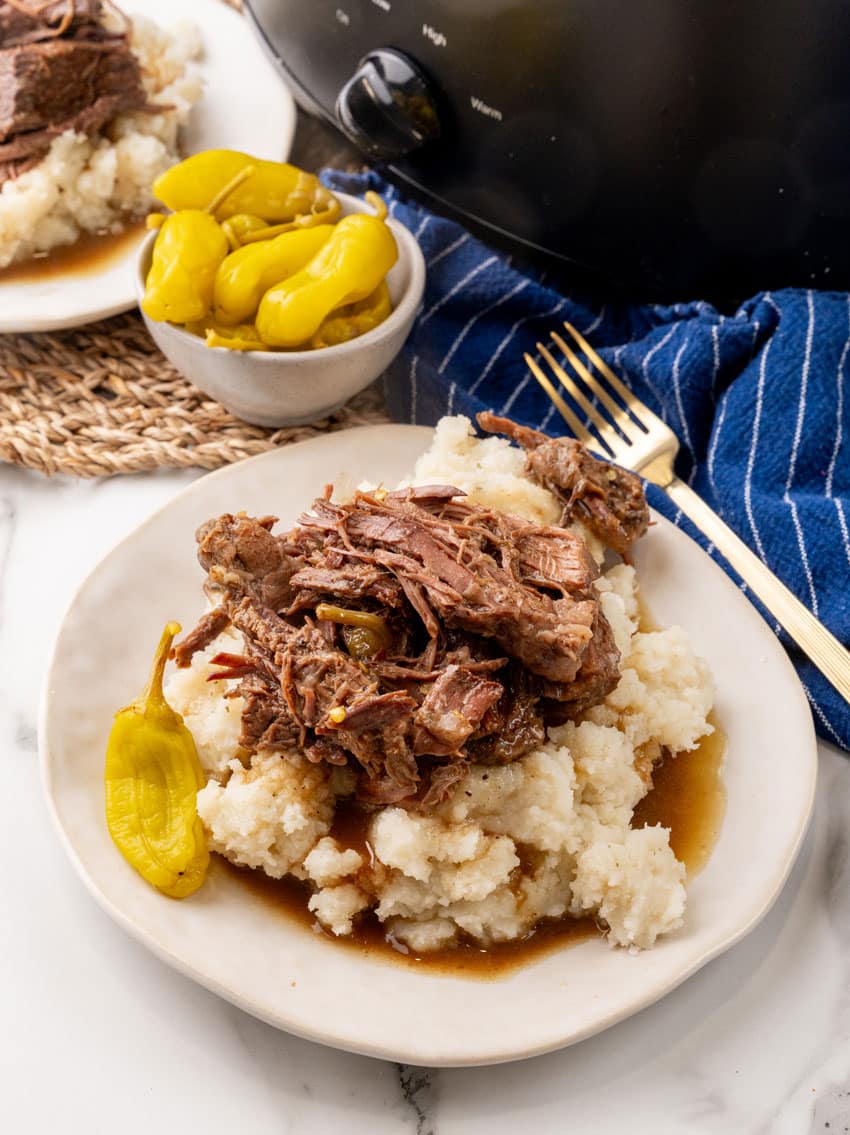 slow cooked mississippi pot roast over mashed potatoes on a white plate