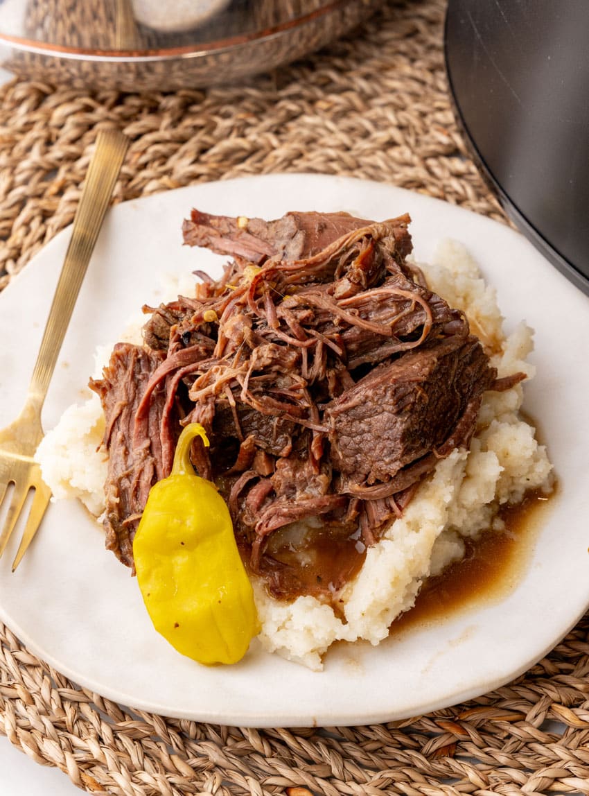 slow cooked mississippi pot roast over mashed potatoes on a white plate
