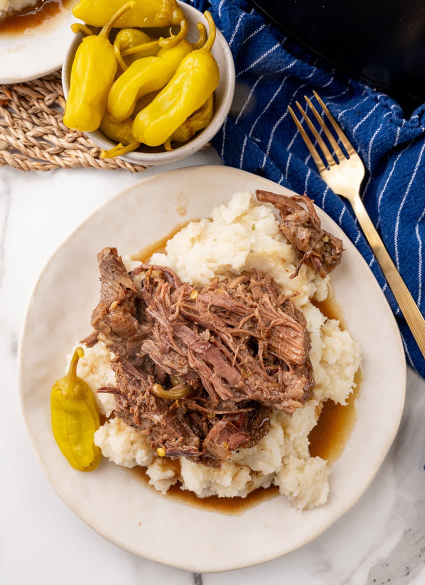slow cooked mississippi pot roast over mashed potatoes on a white plate