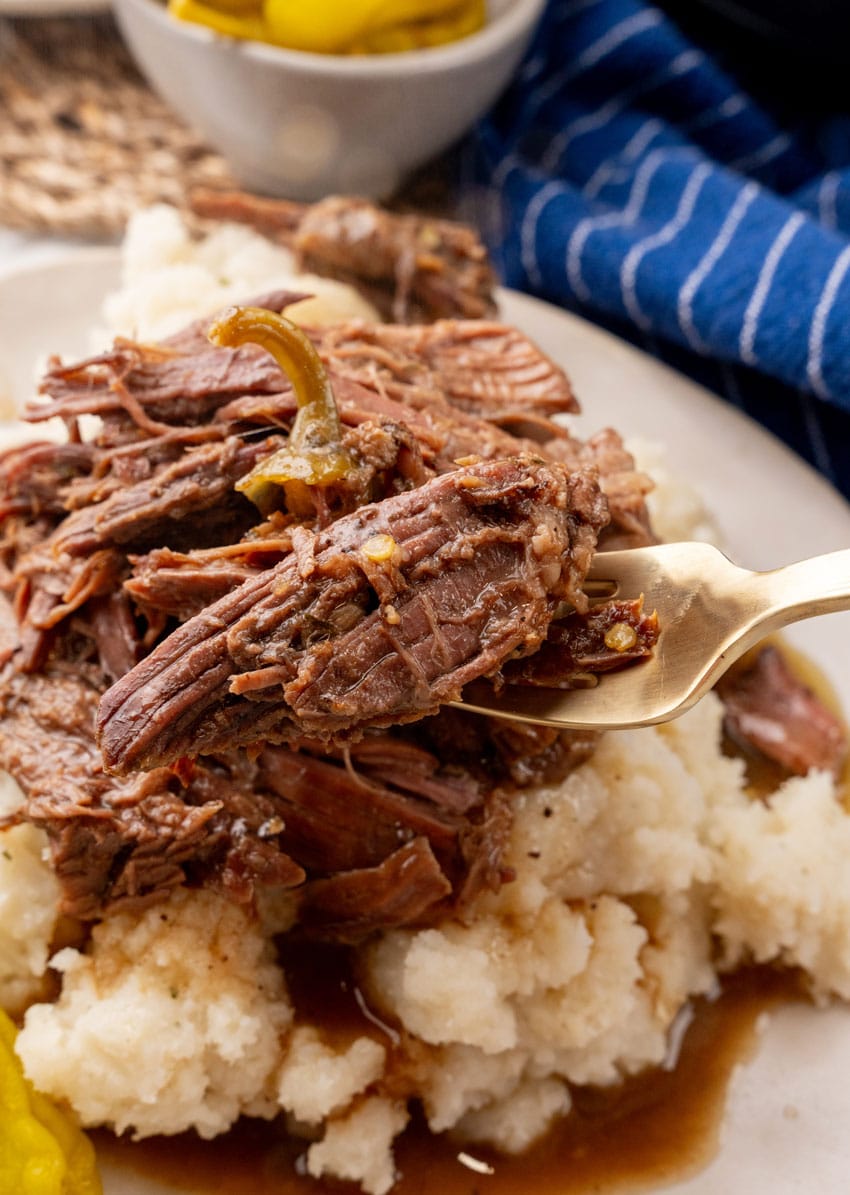 a silver fork holding up a scoop slow cooker mississippi pot roast