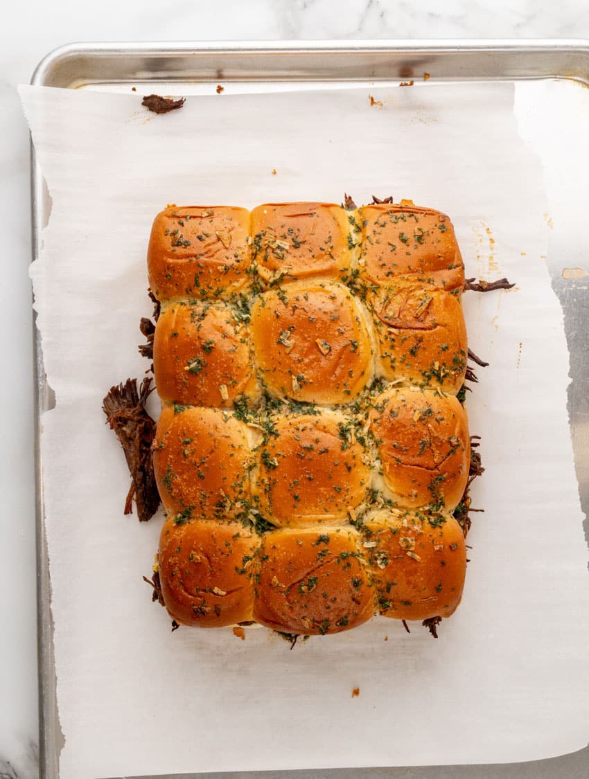 baked mississippi pot roast sliders on a parchment paper lined baking sheet