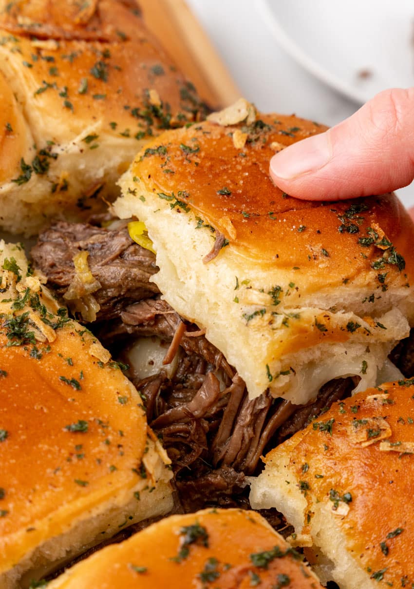 a hand pulling apart mississippi pot roast sliders
