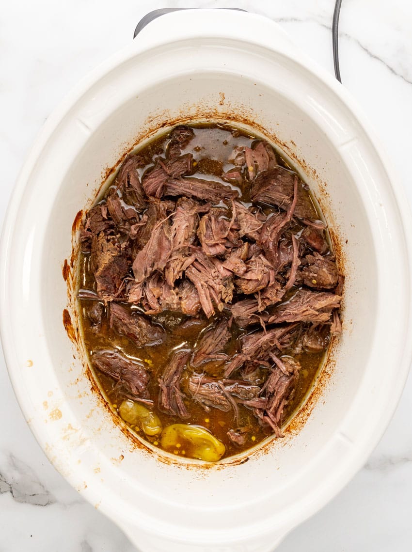shredded mississippi pot roast in the bowl of a white slow cooker