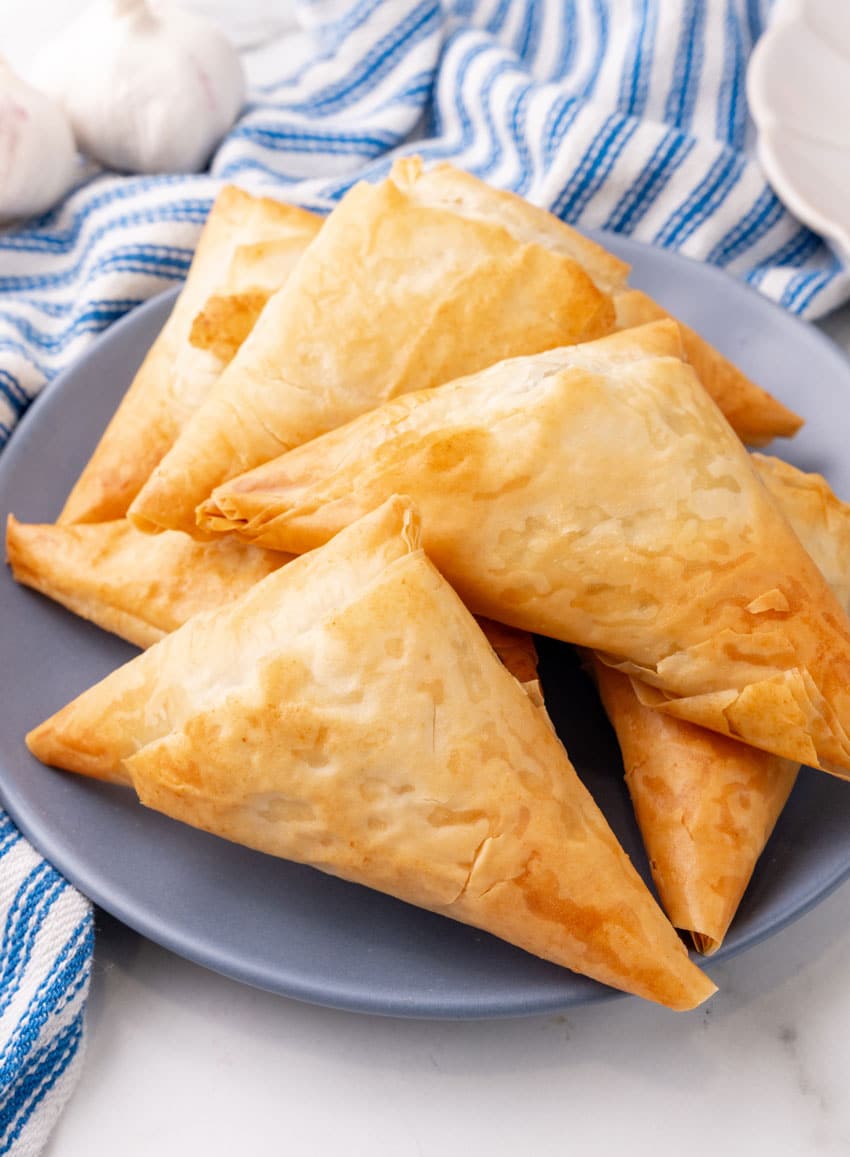 crispy baked spanakopita piled on a small gray plate
