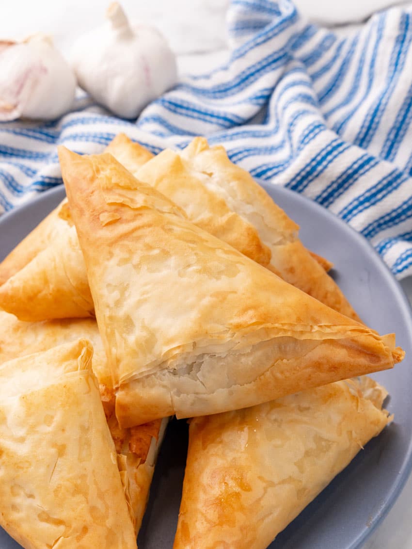 crispy baked spanakopita piled on a small gray plate